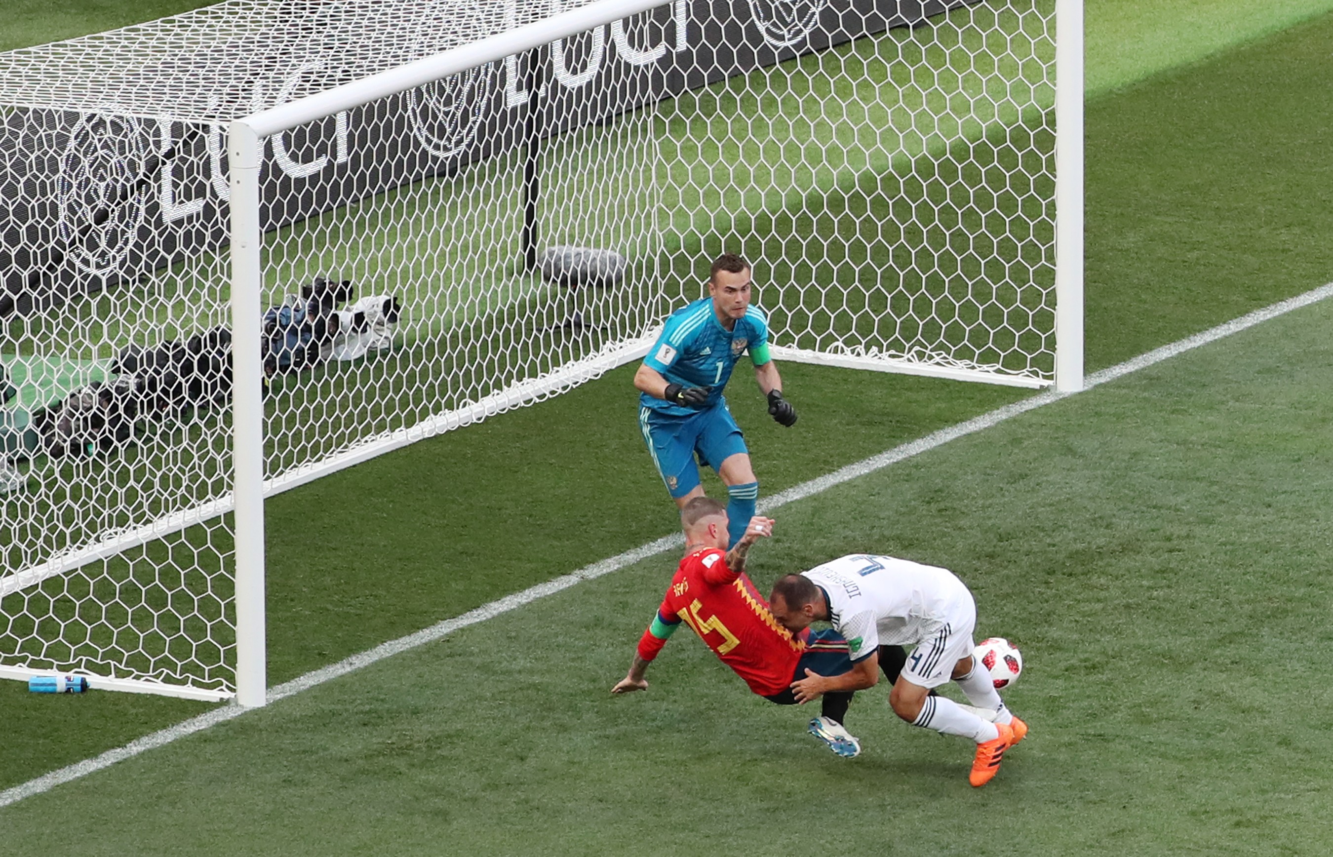 epa06854979 The ball hits the calf of Sergei Ignashevich of Russia from which he scores an goal while in action against Sergio Ramos (red shirt) of Spain during the FIFA World Cup 2018 round of 16 soccer match between Spain and Russia in Moscow, Russia, 01 July 2018.
(RESTRICTIONS APPLY: Editorial Use Only, not used in association with any commercial entity - Images must not be used in any form of alert service or push service of any kind including via mobile alert services, downloads to mobile devices or MMS messaging - Images must appear as still images and must not emulate match action video footage - No alteration is made to, and no text or image is superimposed over, any published image which: (a) intentionally obscures or removes a sponsor identification image; or (b) adds or overlays the commercial identification of any third party which is not officially associated with the FIFA World Cup) EPA-EFE/ABEDIN TAHERKENAREH EDITORIAL USE ONLY